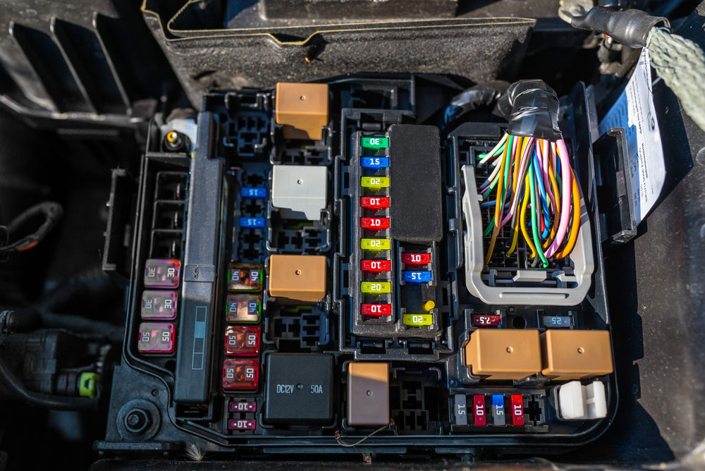 plastic fuse box inside the engine compartment, visible fuses, relays, and cable harnesses